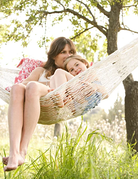 Madre e hija juntas en una hamaca en un jardín casero — Foto de Stock