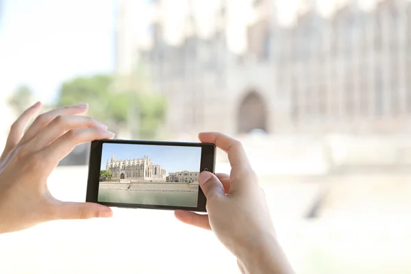 Woman taking photos of a monument cathedral — Stock fotografie