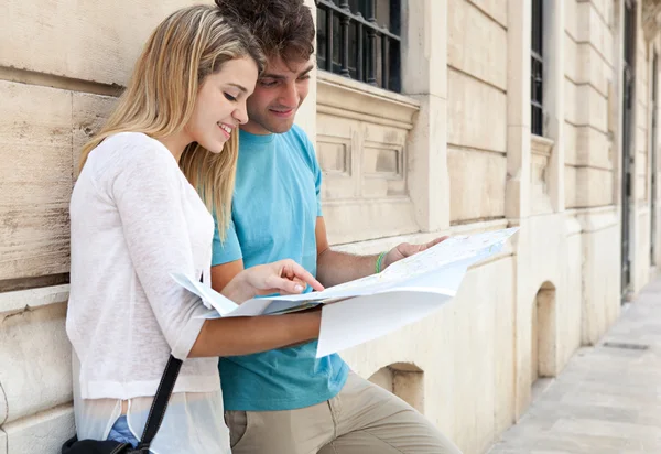 Pareja mirando y apuntando a un mapa — Foto de Stock