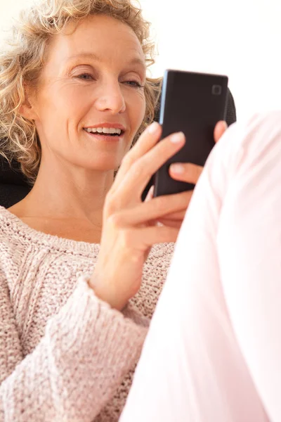 Woman in an armchair using a smartphone — 图库照片