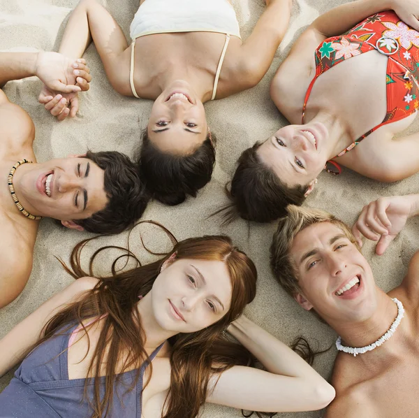 Girls laying down together on a sand beach — 图库照片