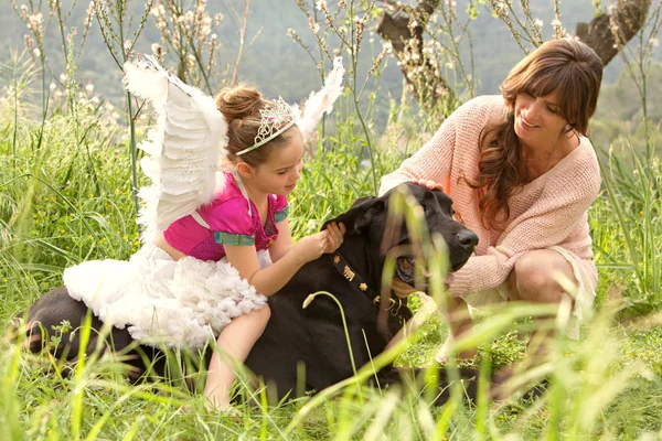 Mother and daughter with their dog in a field — ストック写真