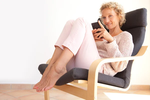 Woman in an armchair using a smartphone — Stock Photo, Image