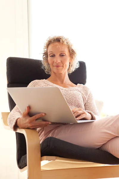 Mulher em uma poltrona usando um computador portátil — Fotografia de Stock