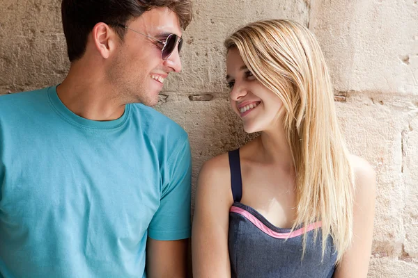 Pareja sonriendo contra un viejo muro de piedra —  Fotos de Stock