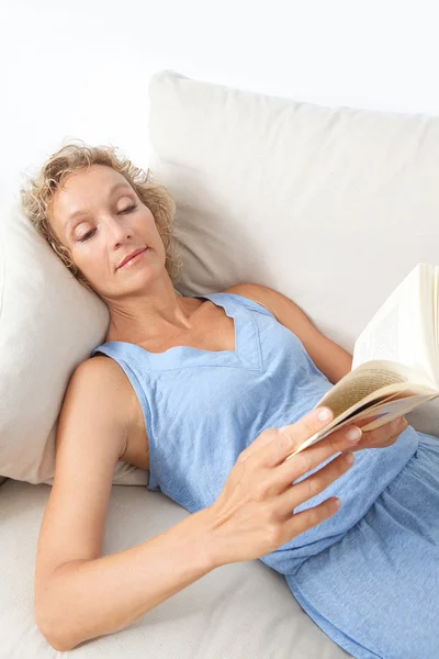 Frau liest Buch zu Hause auf dem Sofa — Stockfoto