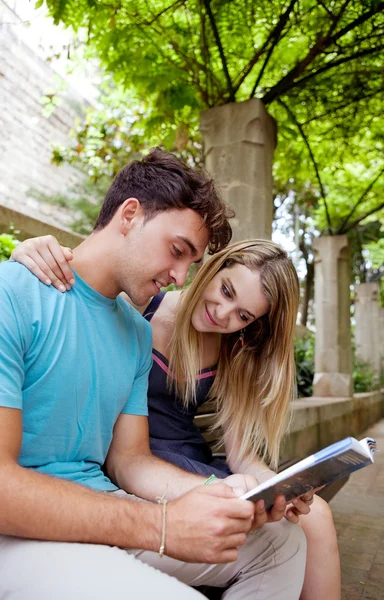 Pareja leyendo a un guía reservar un parque de jardín —  Fotos de Stock