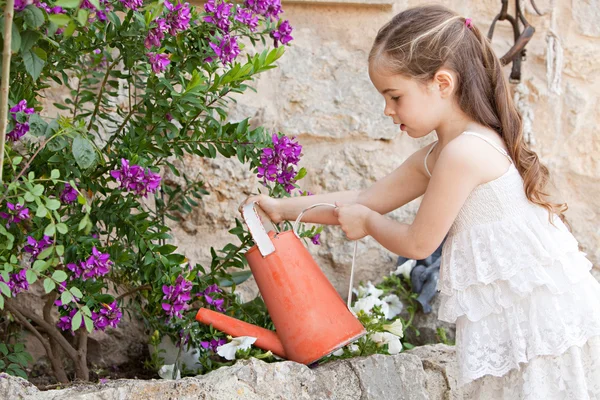 Girl watering the plants in her garden — Stockfoto