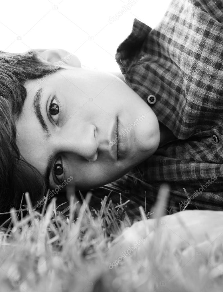 thoughtful teenager boy laying down on grass