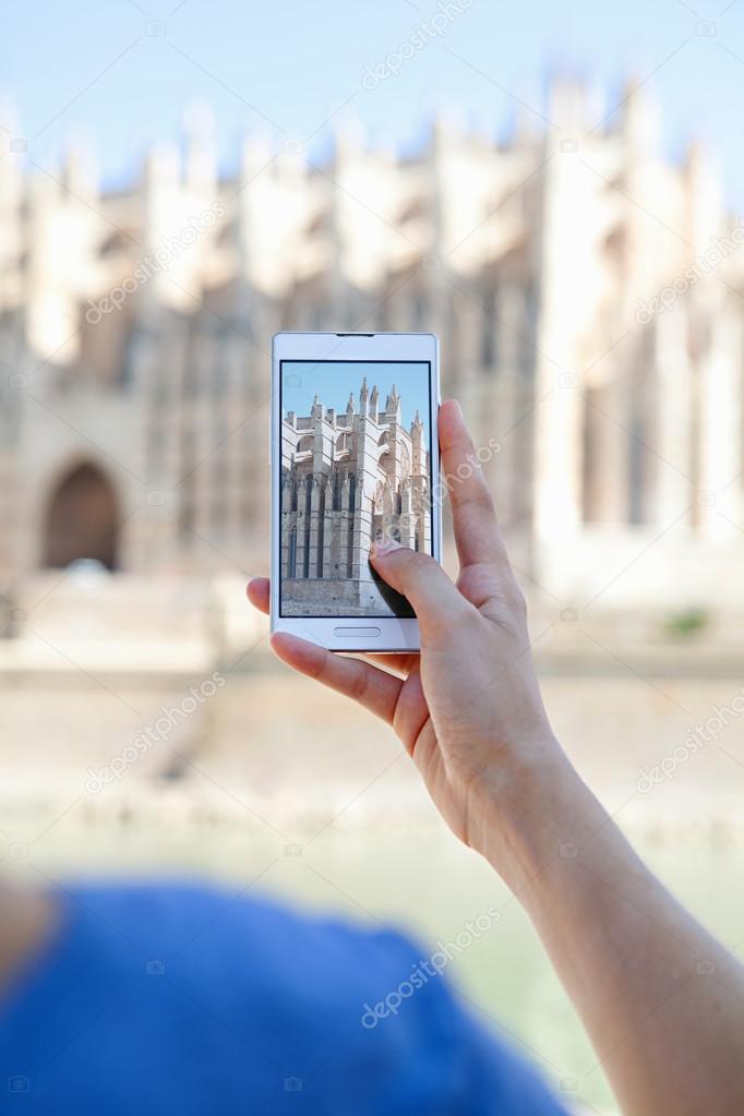 girl using a smartphone to take photos of a cathedral