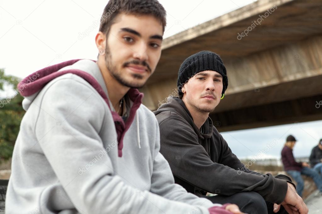 two teenagers friends sitting at a skateboarding park