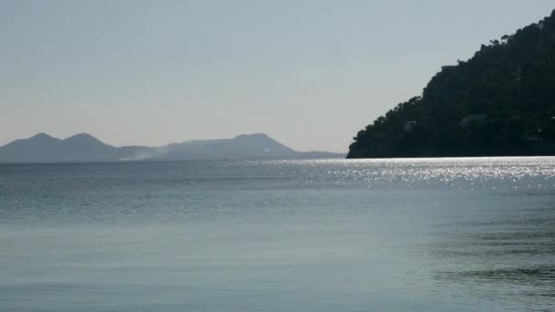 Blick auf glitzerndes Meer mit sanften Bergen — Stockvideo