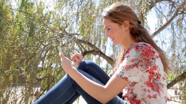 Vrouw met behulp van een smarphone in het park — Stockvideo