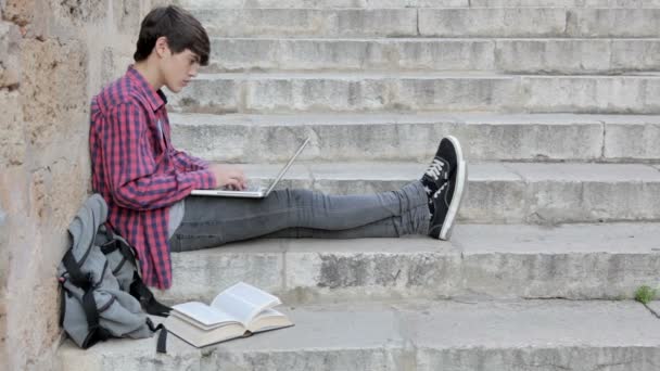 Estudiante haciendo su tarea mientras escribe en su computadora portátil — Vídeos de Stock