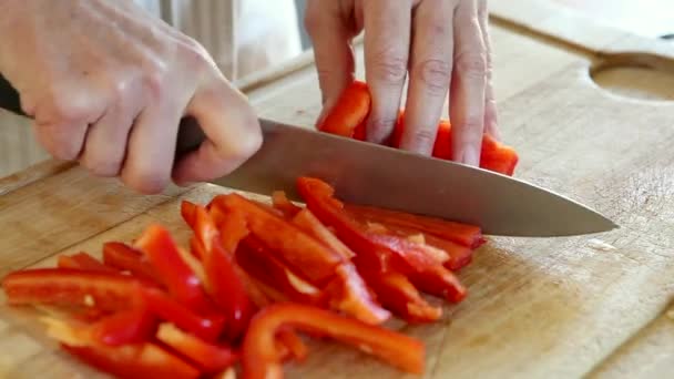 Manos de mujer picando pimientos rojos en una tabla de cortar — Vídeos de Stock