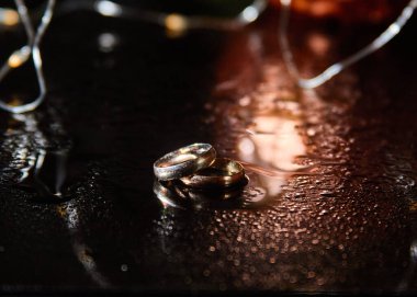 Evlilik yüzükleri. Yüzükler güzel bir ışıkla işaretlenmiş. Bir yüzükte elmas var. Nikah yüzükleri düğün gününün temel özelliğidir.