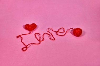 Renkli arka planda bir yün yumağını ve kalp şeklini kapatın. Kalp şeklinde yün iplik. Tığ işini severim. Sevgililer Günü minimum konsept. Kalpli tebrik kartı. Düz yatıyordu. Boşluğu kopyala.