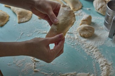Çiğ chebureks, calzone veya qutab, masada kıyma ve soğan. Kadının elleri ev yapımı qutab, chebureki ve calzone yapıyor. Azerbaycan, Tatar, Kafkas, Yunan mutfağı. Latin Amerika 'daki Empanadas 