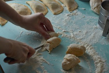 Çiğ chebureks, calzone veya qutab, masada kıyma ve soğan. Kadının elleri ev yapımı qutab, chebureki ve calzone yapıyor. Azerbaycan, Tatar, Kafkas, Yunan mutfağı. Latin Amerika 'daki Empanadas 