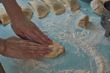 Çiğ chebureks, calzone veya qutab, masada kıyma ve soğan. Kadının elleri ev yapımı qutab, chebureki ve calzone yapıyor. Azerbaycan, Tatar, Kafkas, Yunan mutfağı. Latin Amerika 'daki Empanadas 