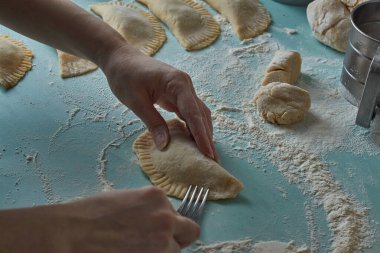 Çiğ chebureks, calzone veya qutab, masada kıyma ve soğan. Kadının elleri ev yapımı qutab, chebureki ve calzone yapıyor. Azerbaycan, Tatar, Kafkas, Yunan mutfağı. Latin Amerika 'daki Empanadas 