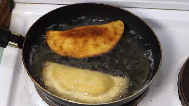 Process with  fried in sunflower oil of homemade chebureks or qutab or calzone with minced meat and onion. Process of making food at the kitchen. Azerbaijani, Tatar, Caucasian, Greek cuisine. Empanadas in Latin America 