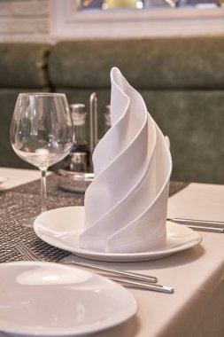 Restoranda güzel servis edilmiş bir masa. Masa seti. Bardaklar, şarap bardakları, çatal bıçak takımı, tabaklar, peçeteler ve atıştırmalıklar. Kafenin içi rahattır.. 