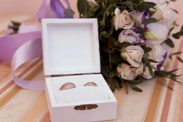 Bridal wedding details, wedding rings. Wooden box for wedding rings  on the background of the bride\'s wedding bouquet, close-up.