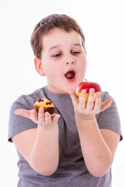 Malý chlapec s jídlem izolovaných na bílém pozadí - apple nebo muffin — Stock fotografie