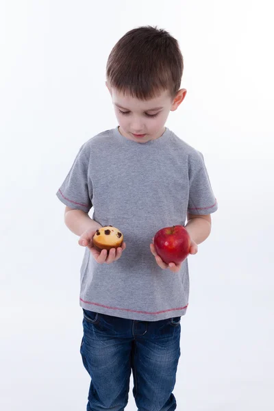 Menino com comida isolada no fundo branco - maçã ou um queque — Fotografia de Stock