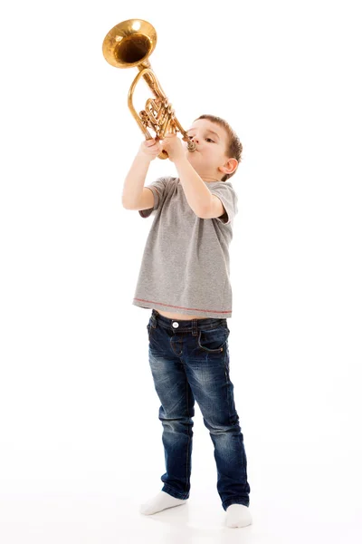 Young boy blowing into a trumpet against white background — Stock Photo, Image