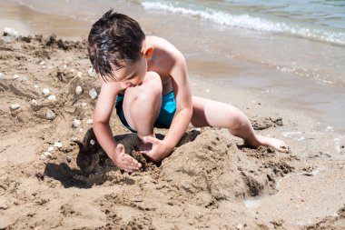 Deniz ve çamur pies ve kum oynarken küçük çocuk