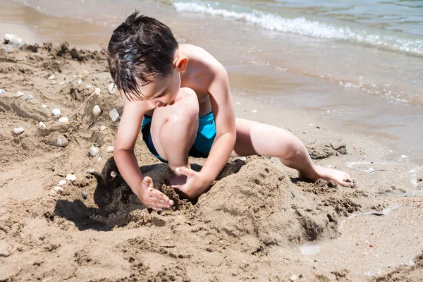 little boy in sea and playing with mud pies and sand