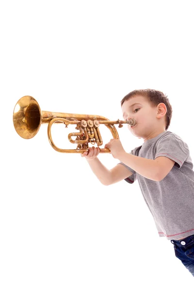 Ung pojke blåser i en trumpet mot vit bakgrund — Stockfoto