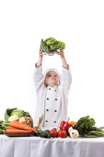 Один маленький мальчик как повар готовит салат, готовит с овощами — стоковое фото
