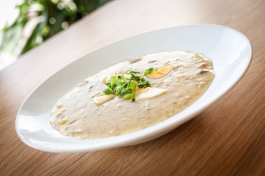 Beyaz tabakta bir restoranda yemek pişirdim. Yumurtalı dereotu çorbası. .