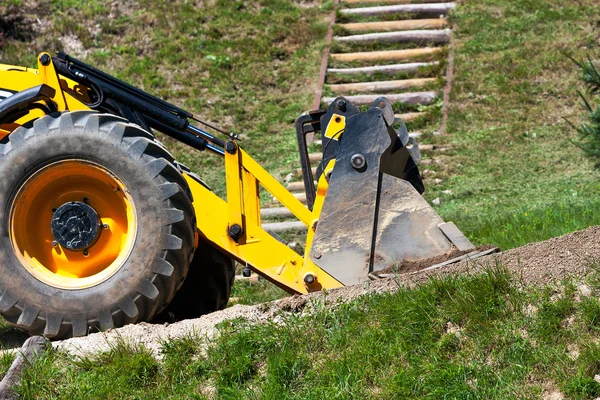 Detalj gula grävmaskin reser på vägen — Stockfoto