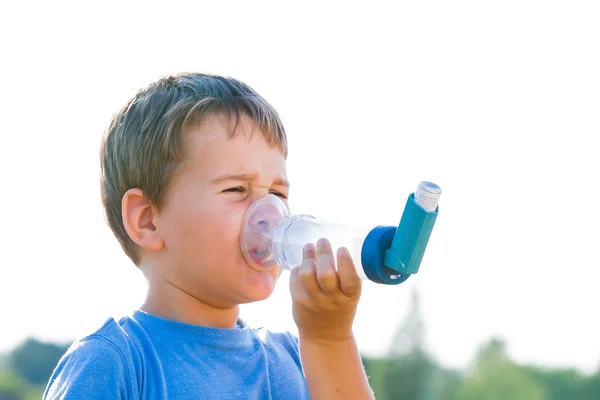 Niño usando inhalador para el asma en la aldea con puesta de sol de verano —  Fotos de Stock