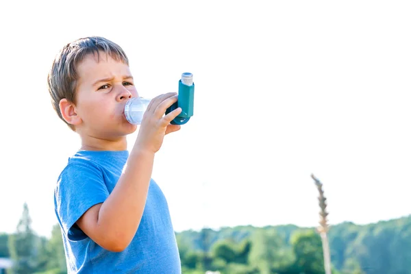 Anak laki-laki menggunakan inhaler untuk asma di desa dengan matahari terbenam musim panas — Stok Foto