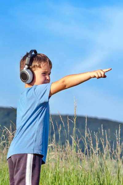 Bonito menino de 6 anos ouvindo música em fones de ouvido na natureza — Fotografia de Stock