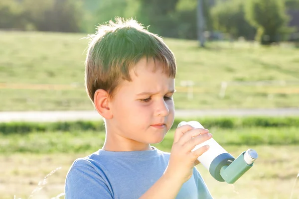 Jongen met behulp van inhalator voor astma in dorp met zonsondergang zomer — Stockfoto