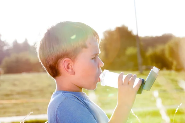 Pojke med inhalator för astma i byn med sommar solnedgång — Stockfoto
