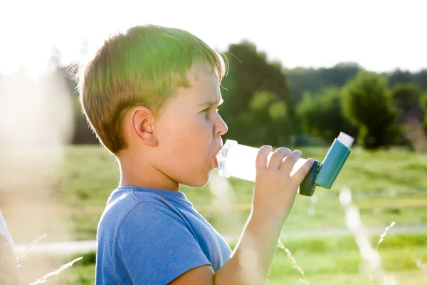 Niño usando inhalador para el asma en la aldea con puesta de sol de verano — Foto de Stock