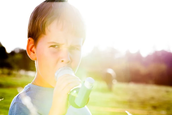 男孩用在村庄的夏天日落景色与哮喘吸入器 — 图库照片