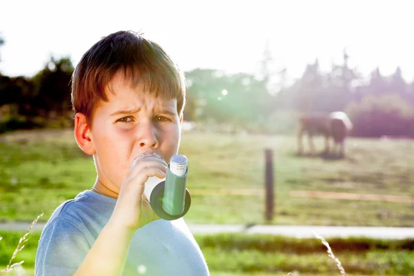 Niño usando inhalador para el asma en la aldea con puesta de sol de verano —  Fotos de Stock