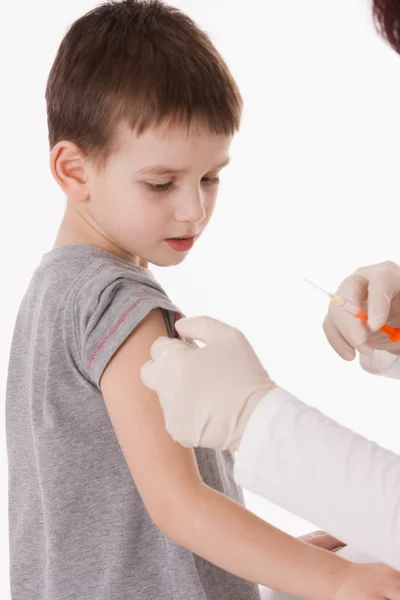 Médico inyectando a un niño en el brazo sobre una imagen aislada . — Foto de Stock