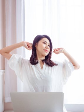 Genç Asyalı kadın dizüstü bilgisayar kullandıktan sonra kollarını açıyor..