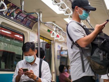 TAIPEI, TAIWAN - 19 Mayıs 2021 tarihinde Tayvan 'ın Taipei kentinde cerrahi maske takan yolcular. 165.096.424 doğrulanmış COVID-19 vakası yaşandı..