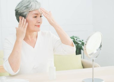 Evde cilt bakımı yapan kıdemli Asyalı kadın..