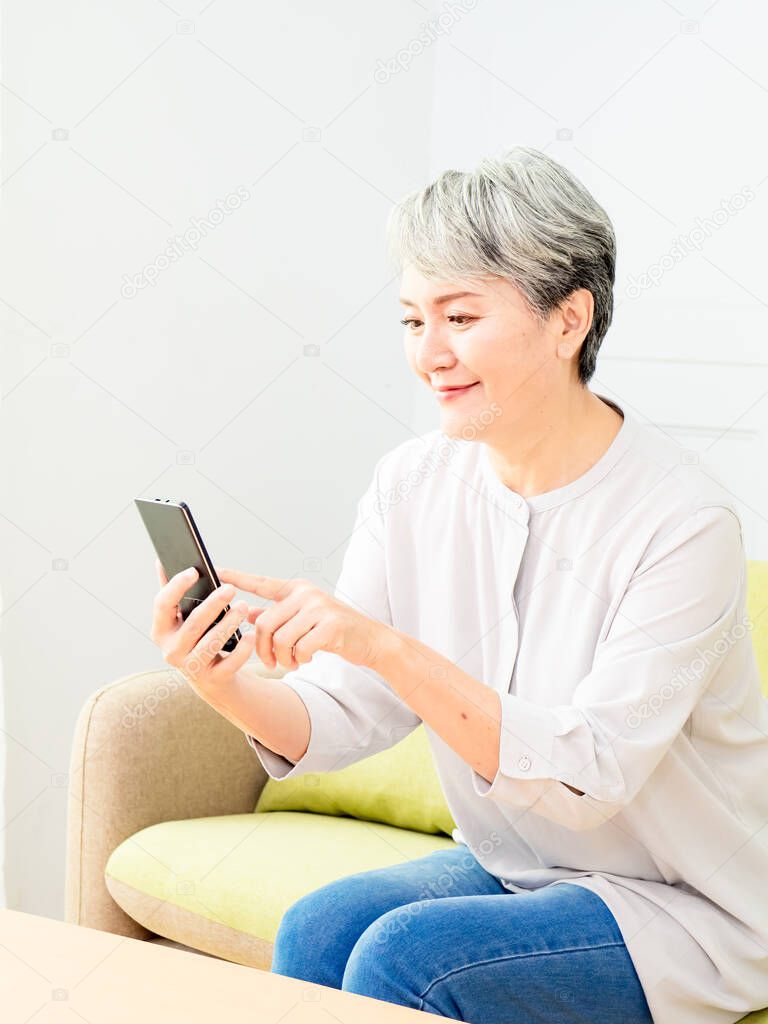 Happy mature senior asian woman holding smartphone using mobile online apps.